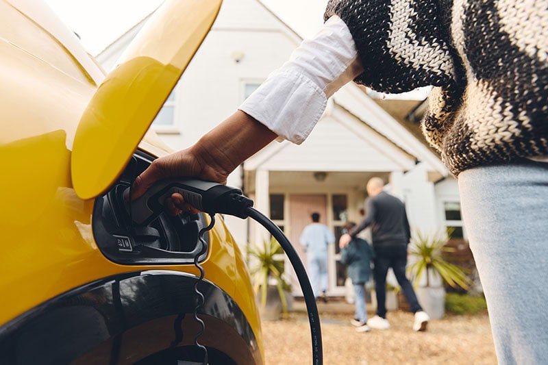 Woman plugging electric charger into her vehicle.