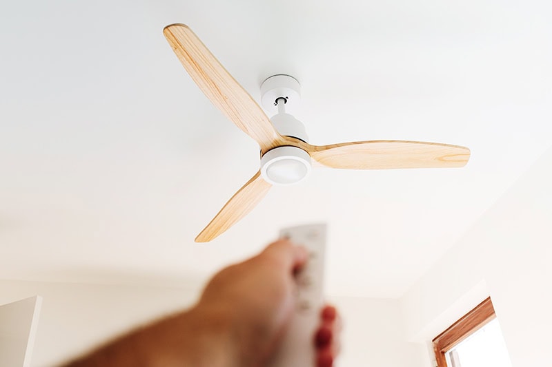 How to Choose the Right Ceiling Fan for Your Space. A person controlling a ceiling fan.