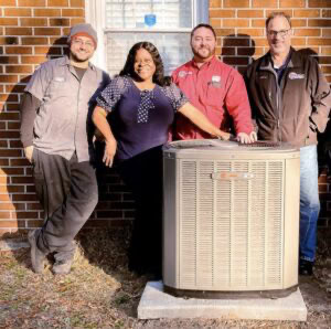 Brunswick County homeowner with standing next to her heat pump with O'Brien Service Company team behind her.