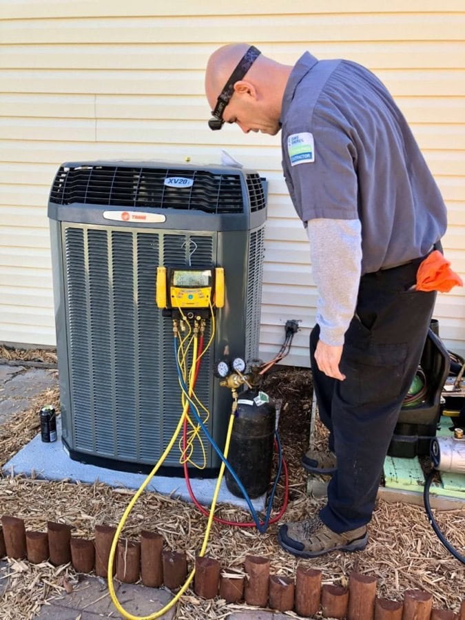 An O'Brien Service Company technician performing air conditioning maintenance.